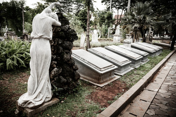 Statue and tombstones in old cemetery Museum Prasasti