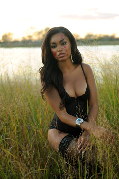 Sexy African-american woman wearing lingerie at the grass field