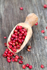 pink peppercorn in a spoon on wooden background