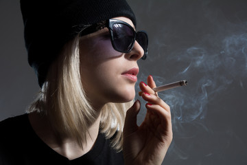 Obraz premium Portrait of a young girl wearing sunglasses smoking a cigarette