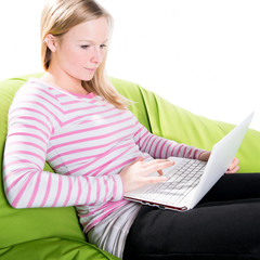 Junge Frau sitzt entspannt mit Notebook auf dem Sofa