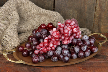 Golden tray with grape on wooden background