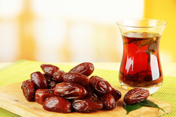 Dried dates with cup of tea on table on bright background