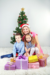 Nice mother and her children with gifts near decorating