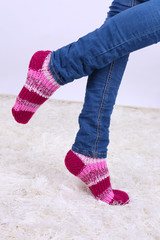 Female legs and  colorful socks on white carpet background