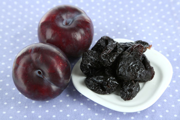 Fresh and dried plums, on color background