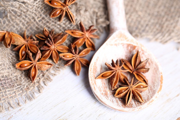 Star anise in wooden spoon, on wooden background