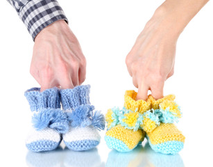 Hands with crocheted booties for baby, isolated on white