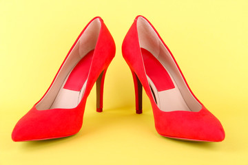 Beautiful red female shoes, on yellow background