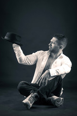 Man portrait playing with hat against dark background. Black and