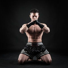 Fototapeta na wymiar Sportsman kick boxer meditation portrait against black backgroun