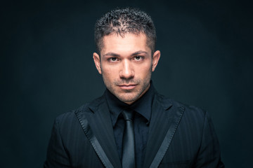 Intense man close up portrait against dark background.
