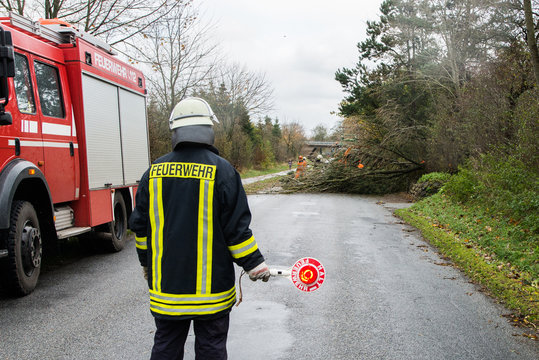 Ein Feuerwehrmann sperrt eine Stra&szlig;e auf der ein Baum liegt