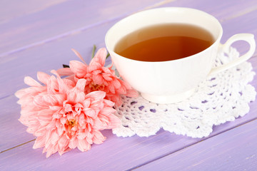 Pink chrysanthemums and cup of tea on wooden table