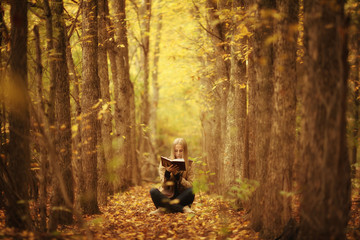 young beautiful girl with a book in the autumn forest