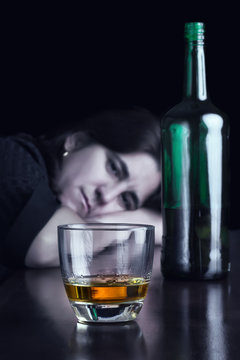Blue toned dark image of a sad drunk woman