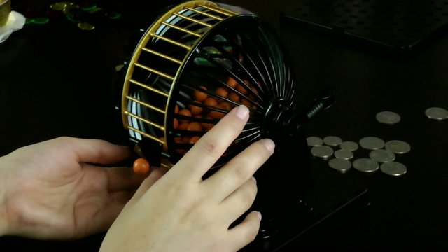 Hands Rolling The Bingo Ball Cage
