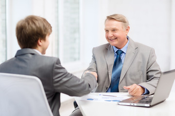 older man and young man shaking hands in office