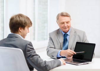 older man and young man with laptop computer