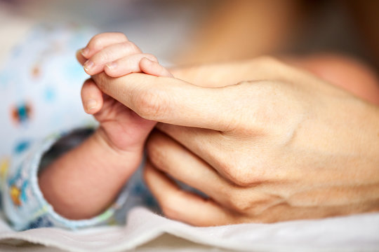 Newborn baby holding mother's hand
