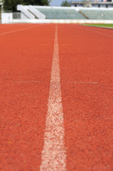 Orange racecourse with white line and grandstand