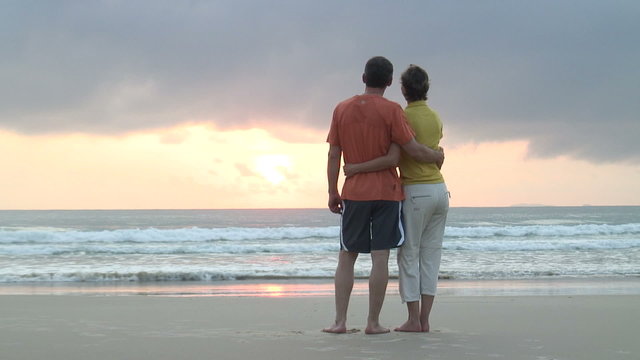 Paar genie&szlig;t Sonnenaufgang am Meer