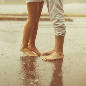 A loving young couple hugging and kissing under a rain. Lovers m