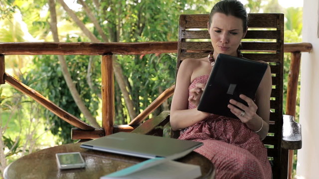 Young woman with tablet computer sitting on house porch