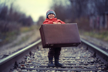 little traveler with a suitcase on the railroad