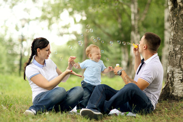 Naklejka premium happy young family mom dad and baby in the park