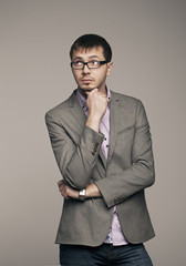 Young man thinking. Studio photo on gray background.