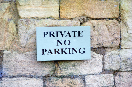 Private no parking sign on stone wall