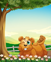 Obraz na płótnie Canvas A bear under the tree near the flowers