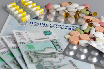 Таблетки и деньги на фоне медицинского полиса