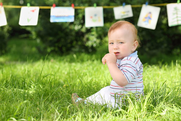 Little boy sitting on the grass in the park