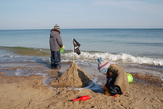 Kinder spielen am Strand im Winter