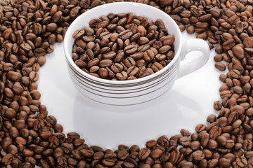 A cup full of coffee beans surrounded by more coffee beans