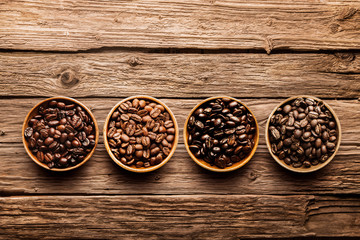 Assorted coffee beans on a driftwood background - obrazy, fototapety, plakaty