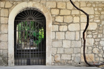 Medieval iron gate in ancient stone wall