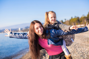 Young mother and adorable little daughter flying like a bird at