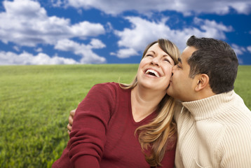 Happy Mixed Couple Sitting in Grass Field