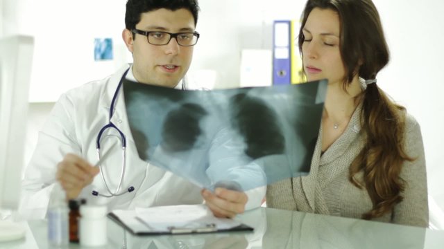 Doctor and Patient Looking at Xray Writing Prescription