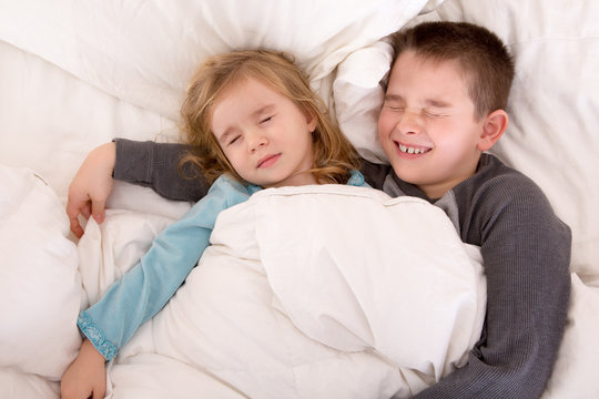 Two cute young children sleeping in bed