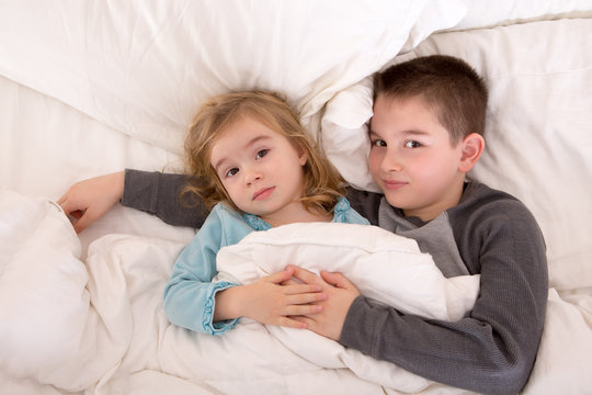 Affectionate young brother and sister lying in bed