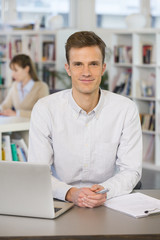 Portrait of smiling businessman working on laptop in office