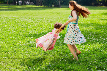 Mother turns little daughter in circle holding her hands