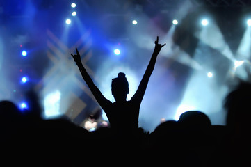 Fototapeta na wymiar Silhouette of a girl with hand in the air on concert