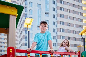 Boy and his younger sister having fun on children playground