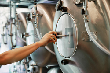 Fototapeta na wymiar Male hand closes hatch of brewery tank