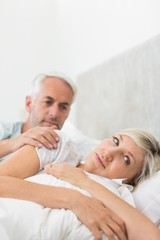 Woman ignoring mature man in bed